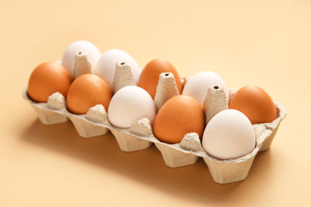 Eggs in cardboard box on beige backgroundの写真素材