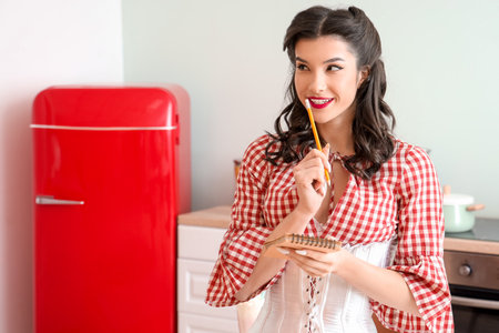 Beautiful pin-up waitress with notebook and pencil in cafeの写真素材
