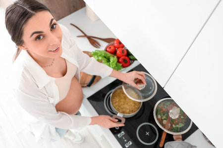 Young pregnant woman cooking pasta in kitchen, top viewの写真素材