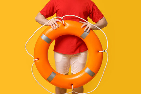 Male lifeguard with ring buoy on yellow background, closeupの写真素材