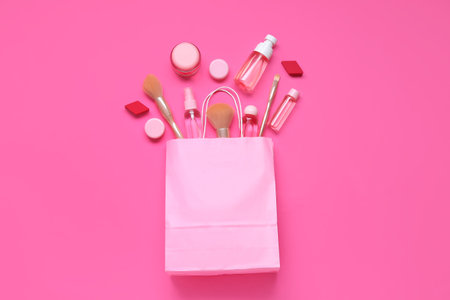 Shopping bag with cosmetic products and makeup accessories on pink backgroundの写真素材