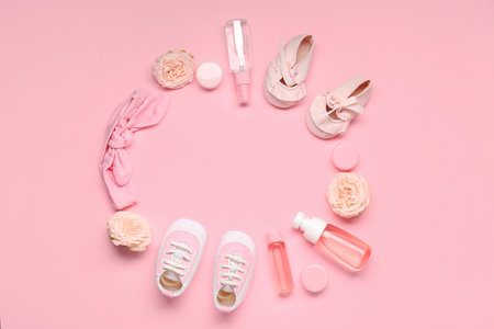Frame made of baby accessories, cosmetics and flowers on pink backgroundの写真素材