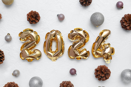 Composition with figure 2024 made of foil balloons and Christmas decorations on white backgroundの写真素材