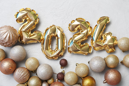 Composition with figure 2024 made of foil balloons and Christmas balls on gray backgroundの写真素材