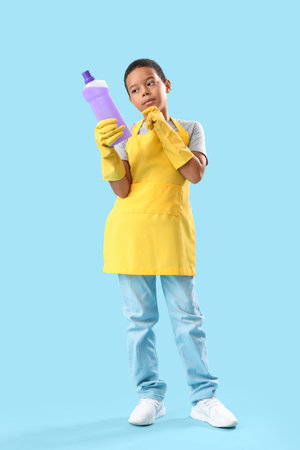 Pondering African-American boy with bottle of detergent on blue backgroundの写真素材