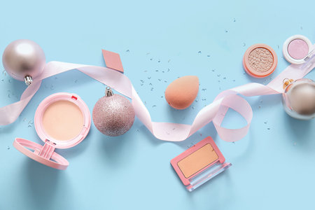 Beautiful pink Christmas decorations and makeup products on blue backgroundの写真素材