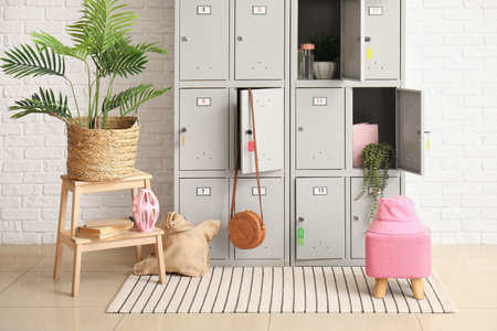 Modern locker with plants, bags and stepladder near white brick wall
