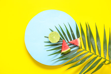 Blank card and pieces of fresh watermelon with palm leaf on yellow backgroundの写真素材