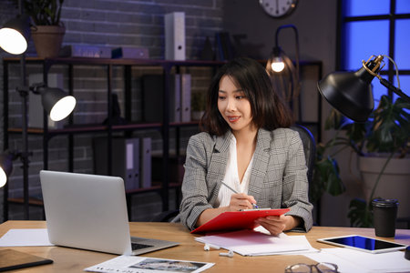 Happy Asian businesswoman sitting at table and working in officeの写真素材