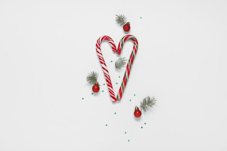Christmas balls, candy canes and fir branches on white background