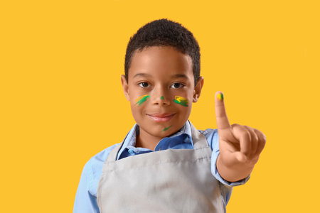 Little African-American boy with face in paint on yellow background, closeupの写真素材