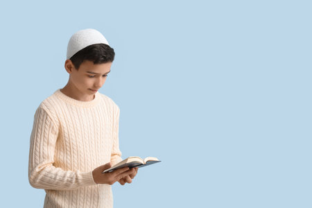 Little Muslim boy with Quran on light blue backgroundの写真素材