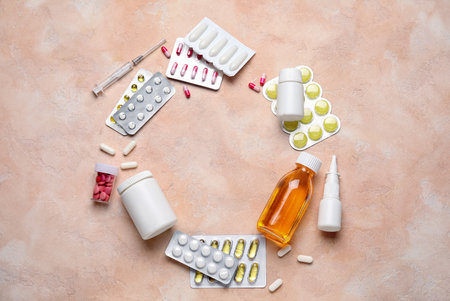 Frame made of different pills, syringe and bottles of medicines on pink backgroundの写真素材