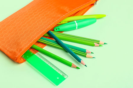 Pencil case with different stationery on color background, closeup