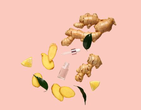 Flying slices of fresh ginger root and cosmetic bottle on pink backgroundの写真素材