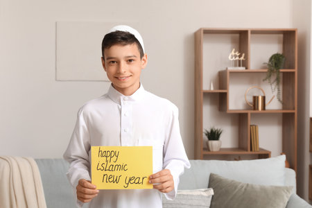 Little Muslim boy with greeting card for Islamic New Year at homeの写真素材