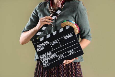 Beautiful woman with movie clapper and sombrero hat on green backgroundの写真素材