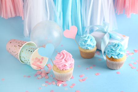 Delicious cupcakes with gift box and decorations on blue background. Gender reveal party conceptの写真素材