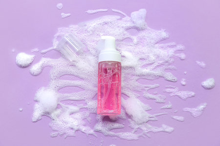 Bottle of skin care cosmetic product with foam on lilac background
