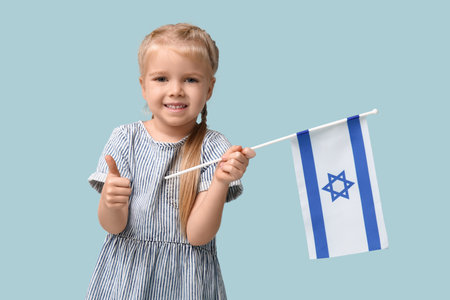 Cute happy little girl with Israel flag on blue background. Hanukkah celebrationの写真素材
