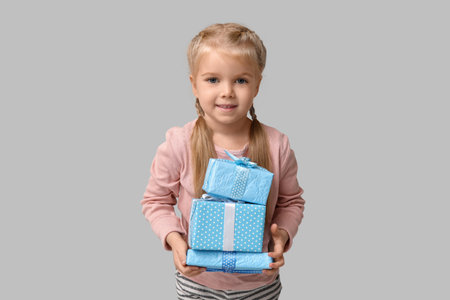Cute happy little girl with gift boxes on gray background. Hanukkah celebrationの写真素材
