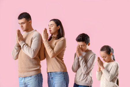 Family praying together on pink backgroundの写真素材