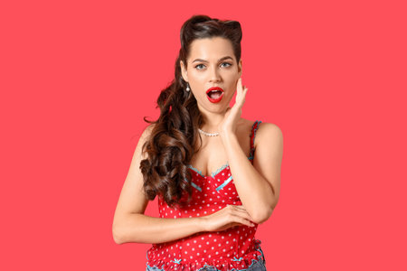 Portrait of surprised pin-up woman on red backgroundの写真素材