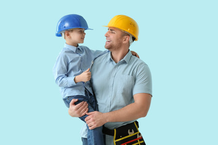 Happy father and his little son in hardhats with tools on blue backgroundの写真素材