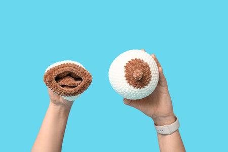 Female doctor's hands with knitted model of breast on blue background. Breast feeding concept