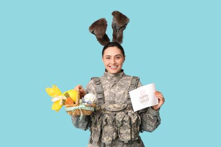 Happy female soldier in bunny ears with greeting card, Easter basket and chocolate egg on blue backgroundの写真素材