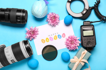 Composition with greeting card, photographer's equipment and Easter decor on blue backgroundの写真素材