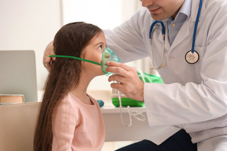 Little girl with doctor using nebulizer in clinicの写真素材
