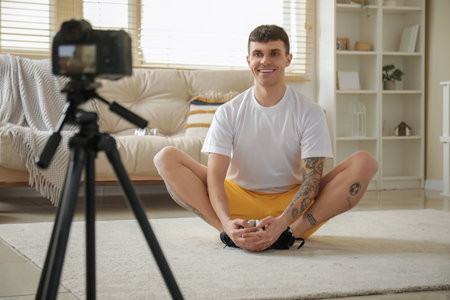 Sporty happy male blogger recording video while training at homeの写真素材