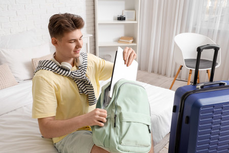 Male tourist taking laptop from backpack in hotel roomの写真素材