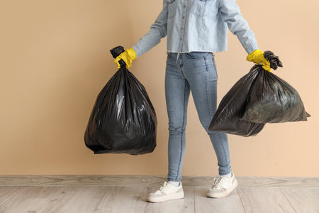 Woman with garbage bags near beige wallの写真素材