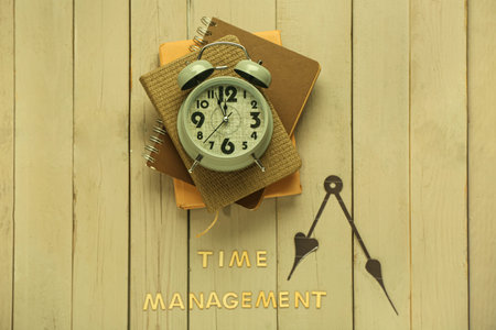 Text TIME MANAGEMENT, alarm clock and notebooks on wooden background. Top view