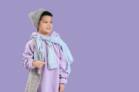 Cute little Asian boy in adult clothes with bag on lilac backgroundの写真素材