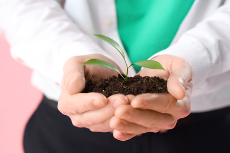 Man holding soil with young plant on pink background, closeup. Ecology conceptの写真素材
