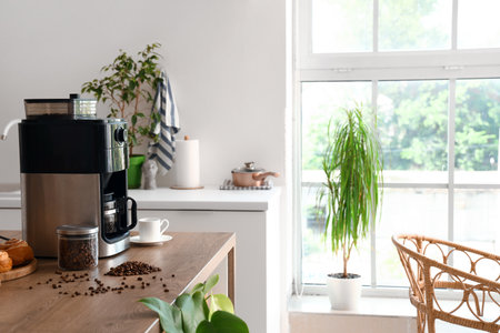 Modern coffee machine with jar of roasted beans and cup on table in kitchenの写真素材