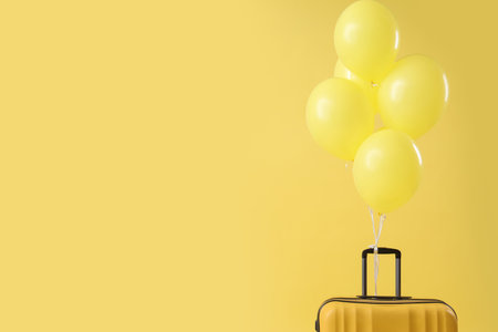 Suitcase with floating balloons on yellow backgroundの写真素材