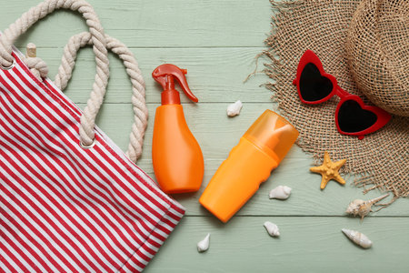 Bag, bottles of sunscreen and beach accessories on wooden background