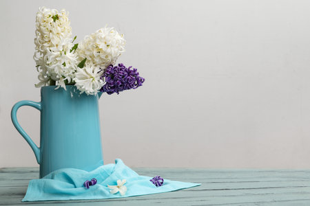 Beautiful hyacinth flowers in blue vase on table against white backgroundの写真素材