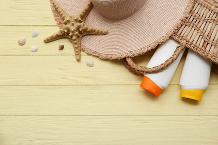 Bottles of sunscreen, starfish and beach accessories on wooden background