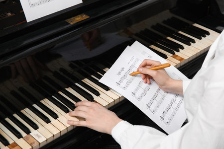 Woman playing piano and writing notes, closeupの写真素材