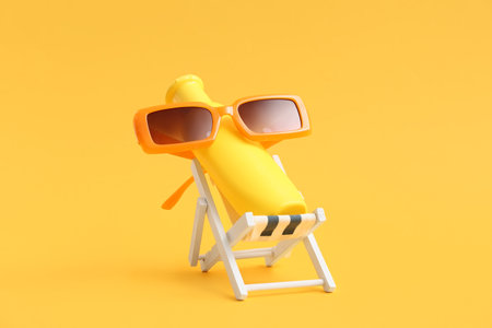 Deckchair with bottle of sunscreen cream and sunglasses on color backgroundの写真素材