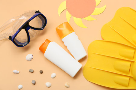 Bottles of sunscreen, diving mask and flippers on orange backgroundの写真素材