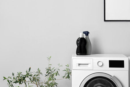Washing machine with bottles of detergent near gray wallの写真素材