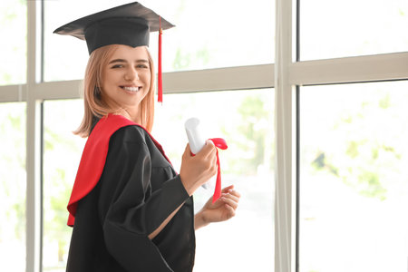 Female graduate student with diploma near window in room