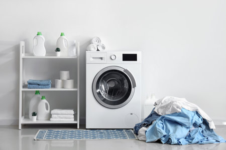 Washing machine, shelving unit and pile of dirty laundry near white wallの写真素材