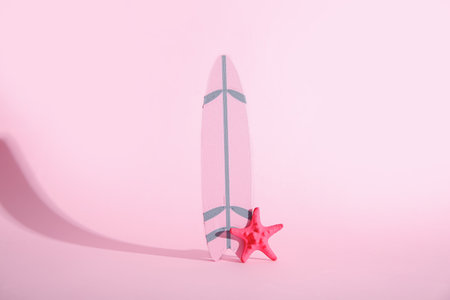 Mini surfboard with starfish on pink backgroundの写真素材